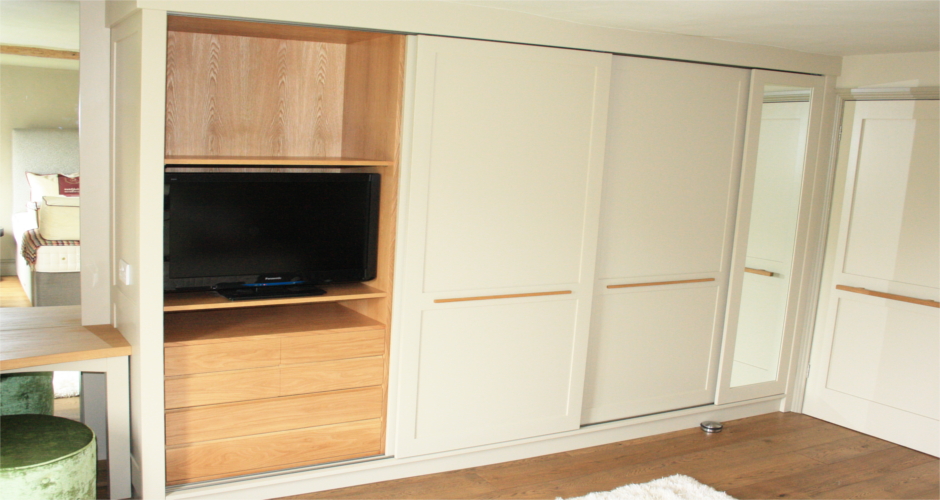 Fitted sliding door wardrobe in painted tulipwood and oak interior